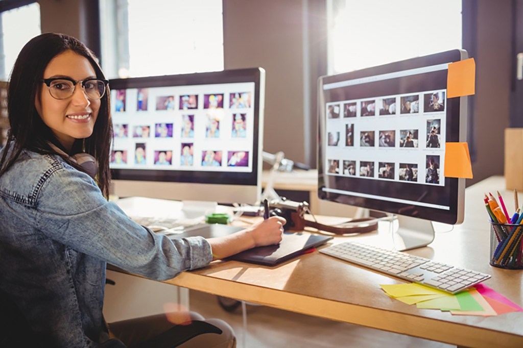 Female graphic designer using graphic tablet while working on computer at office